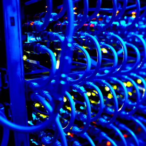 Cabos de rede azuis organizados em data center com LEDs indicadores de atividade e equipamentos de conectividade